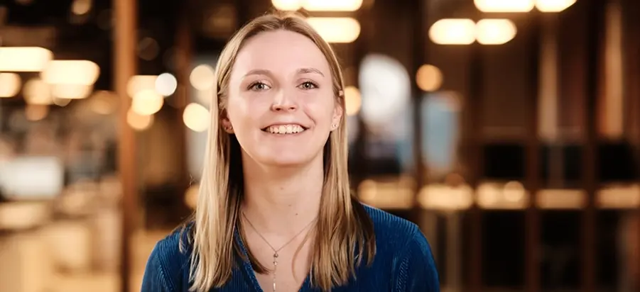 Vrouw met blond haar staat in een Persoonality vestiging en lacht in de camera